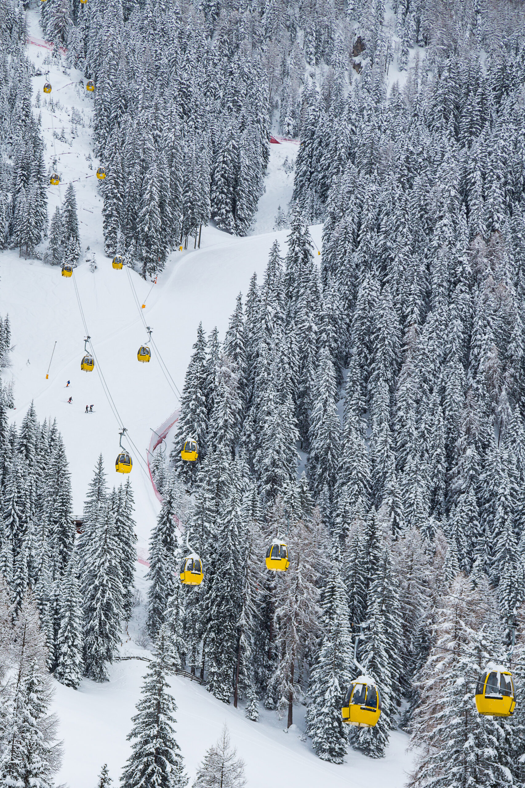 A vertical shot of yellow cable cars in the mountain during winter